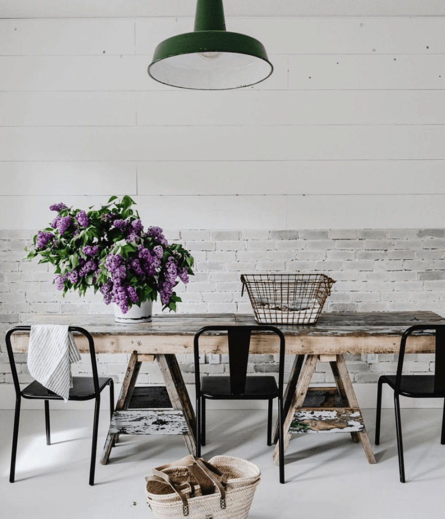 Brick wall and shiplap wall with a raw wood table with lilacs